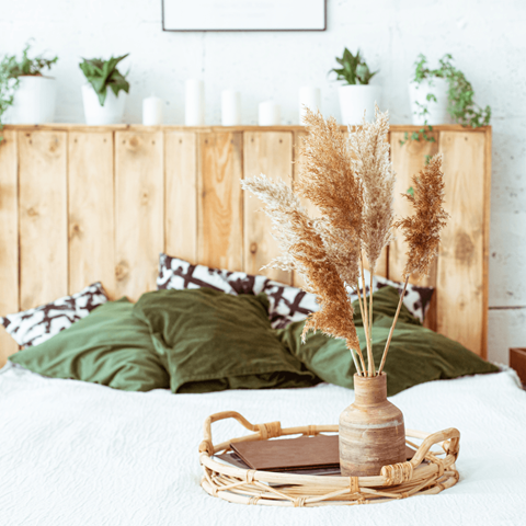 a bed with green pillows and a wooden headboard and a vase of